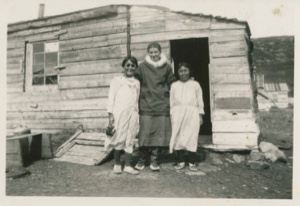 Image of Miriam MacMillan with two Eskimo [Inuit] women in front of their home
